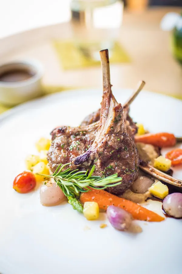 French-trimmed lamb chops plated with roasted vegetables